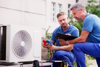 HVAC technicians reviewing an outdoor air conditioning unit in Loveland, CO