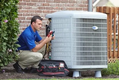 HVAC technician inspecting an outdoor air conditioning unit in Loveland, CO